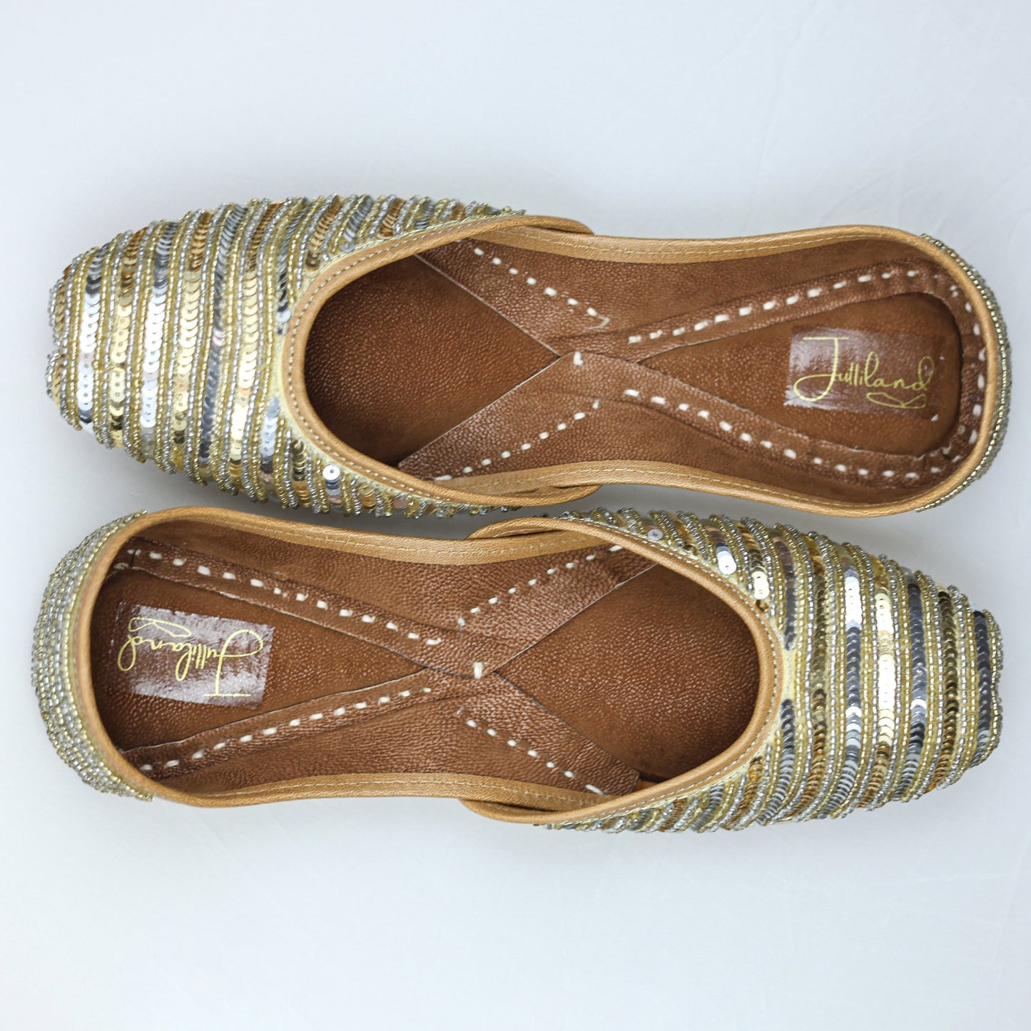 Close-up of handcrafted golden and silver jutti with intricate detailing, perfect for festive occasions and weddings