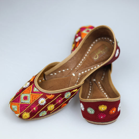 Maroon Phulkari jutti paired with ethnic wear, highlighting vibrant handcrafted design and traditional elegance